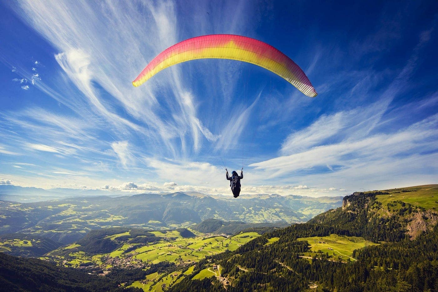 Tandem paraglider soaring above the green ridges of Pithoragarh